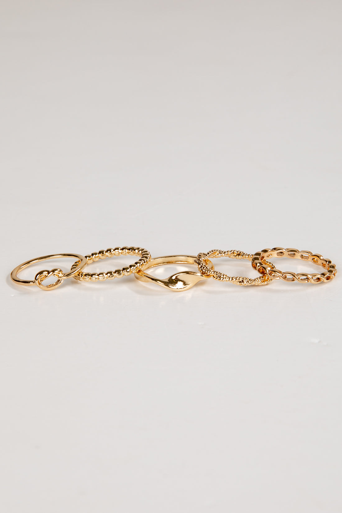 Set of gold chain rings on a light gray background