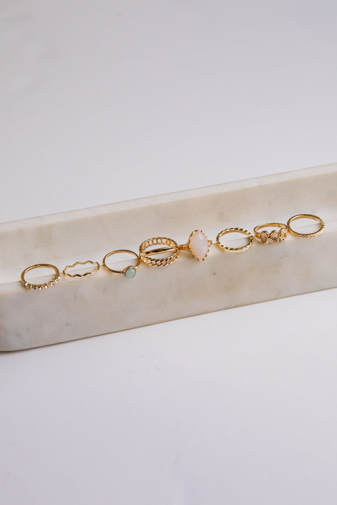 Set of gold rings on a marble surface with a light background