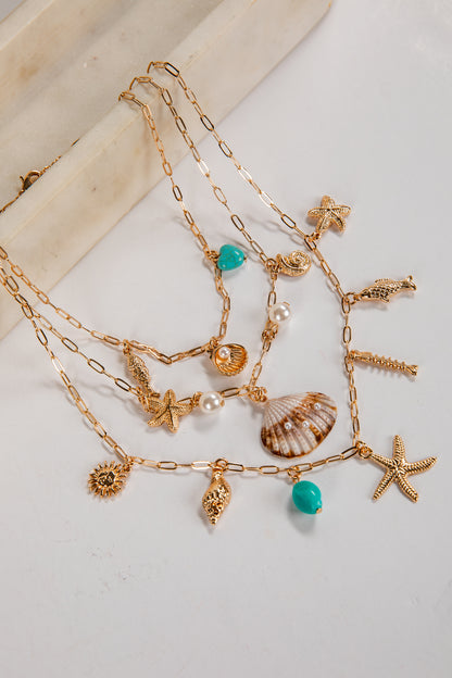 Gold necklaces with various charms on a light background