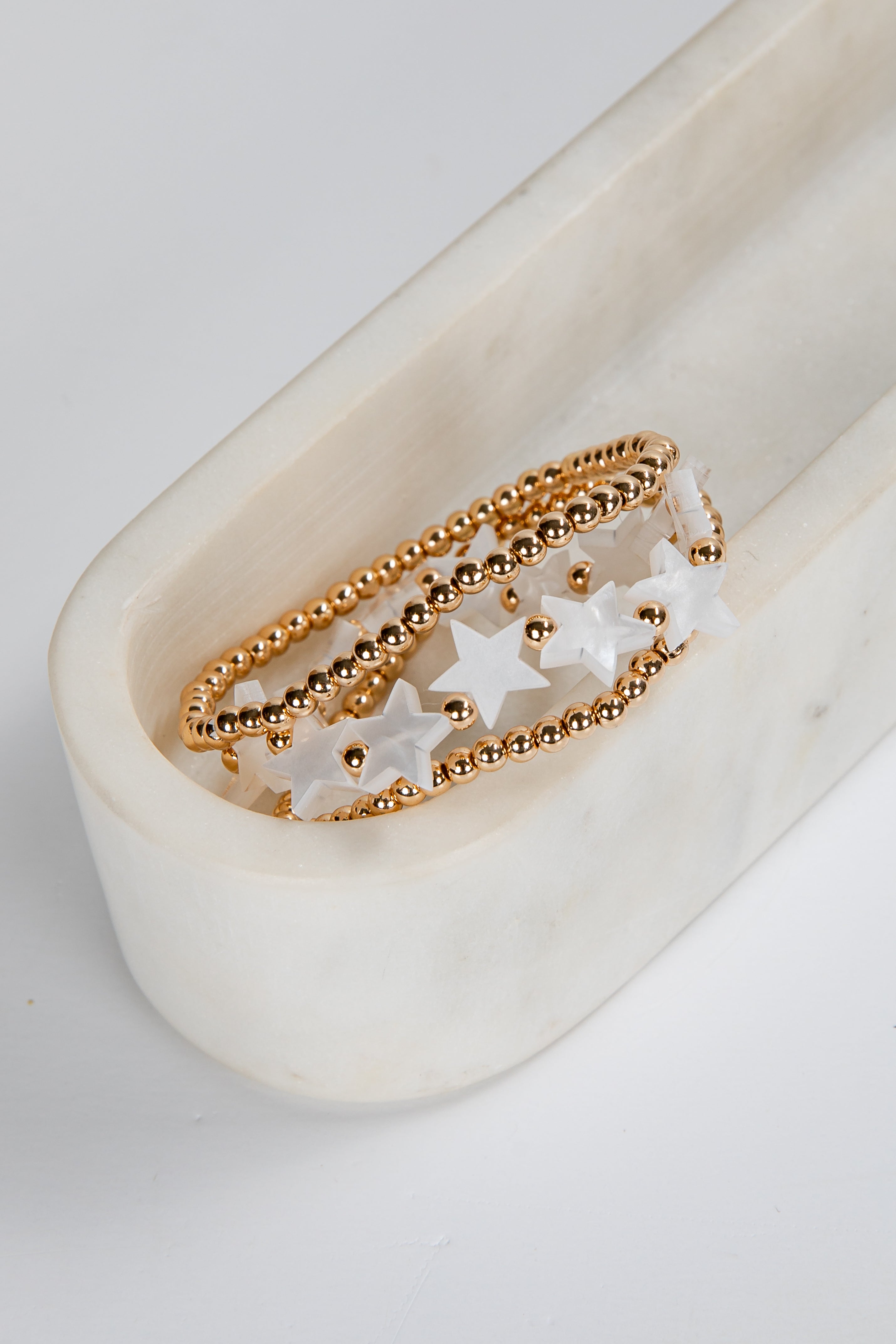 Gold ring with star-shaped stones on a white ceramic dish
