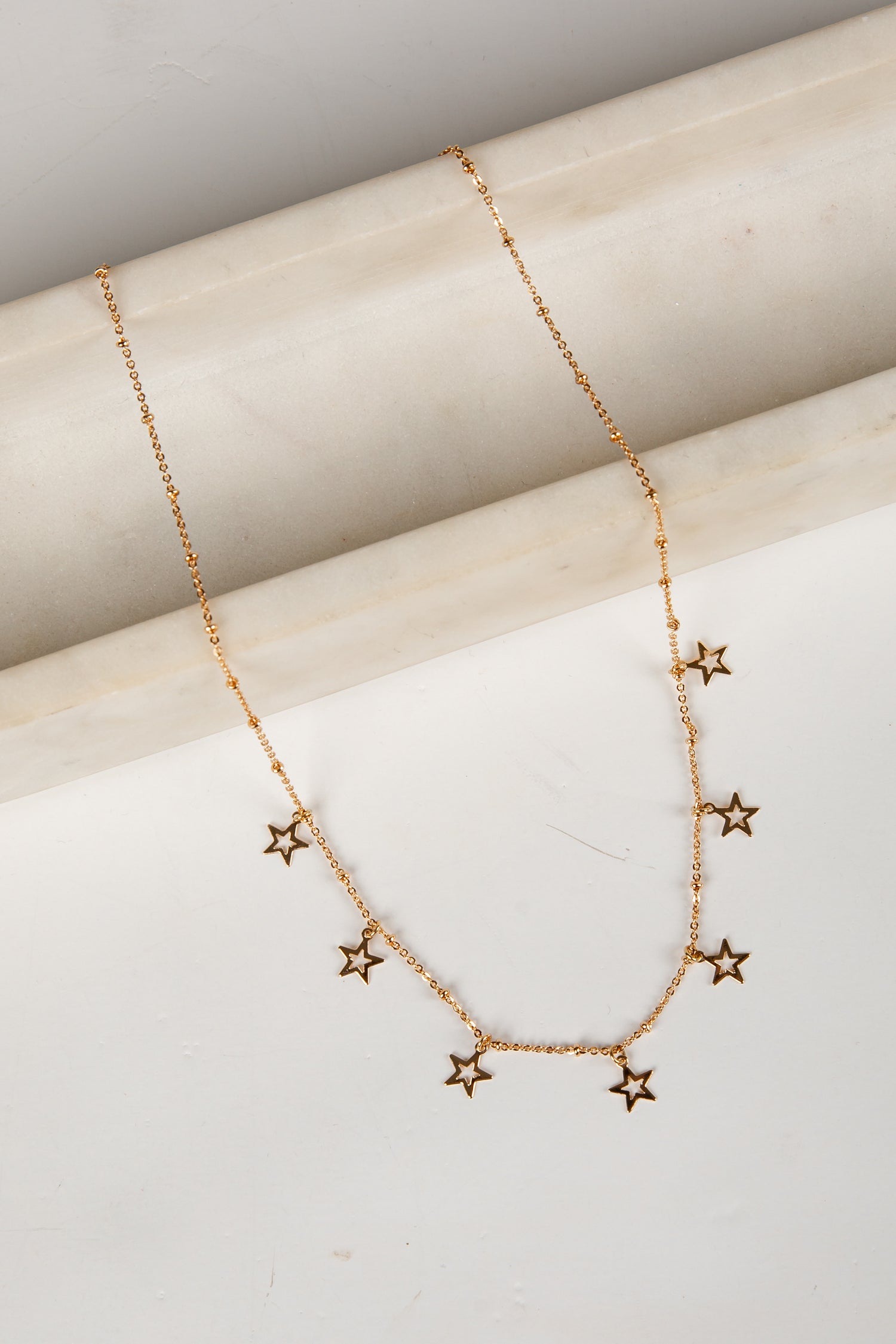 Gold star necklace on a light wooden surface
