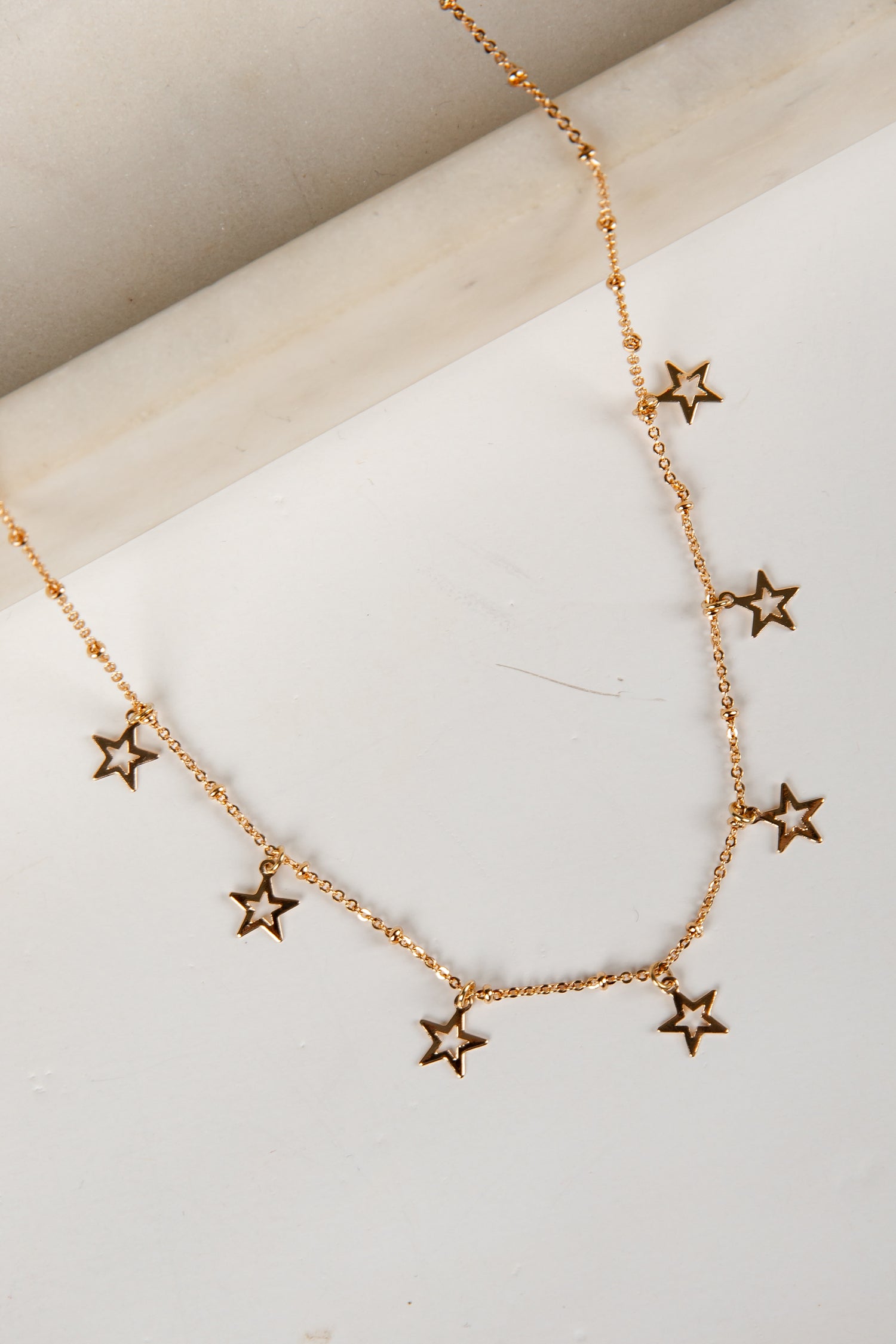 Gold star necklace on a light wooden surface
