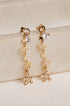 Gold star-shaped earrings with clear stones on a beige surface