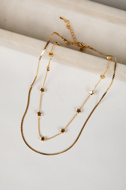 Gold necklace with star-shaped beads on a marble surface