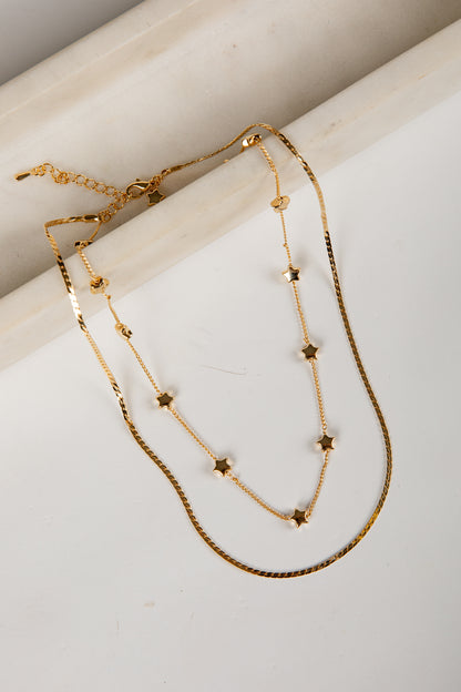 Two gold necklaces with star-shaped beads on a light background