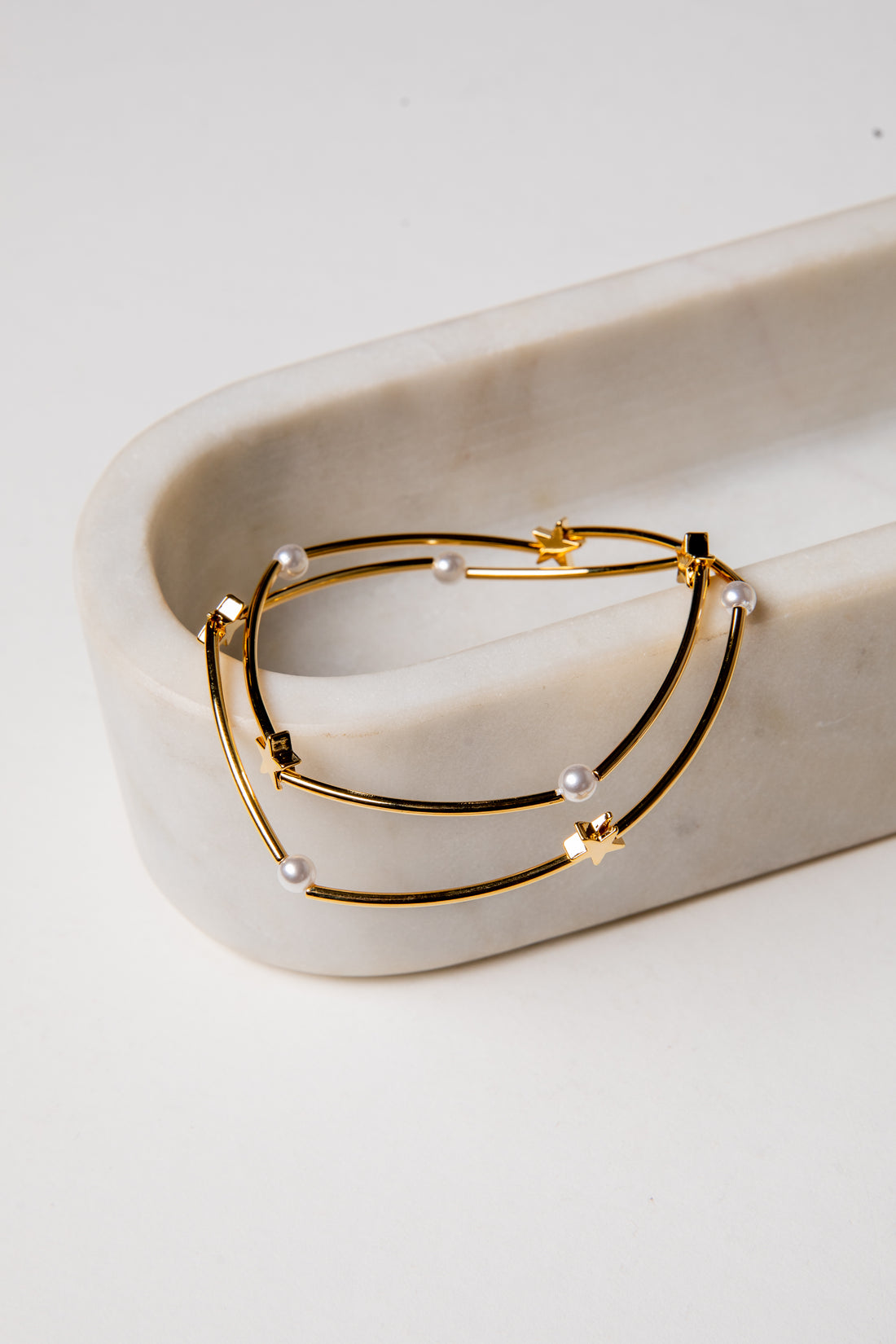 Gold hoop earrings with pearls on a white marble surface