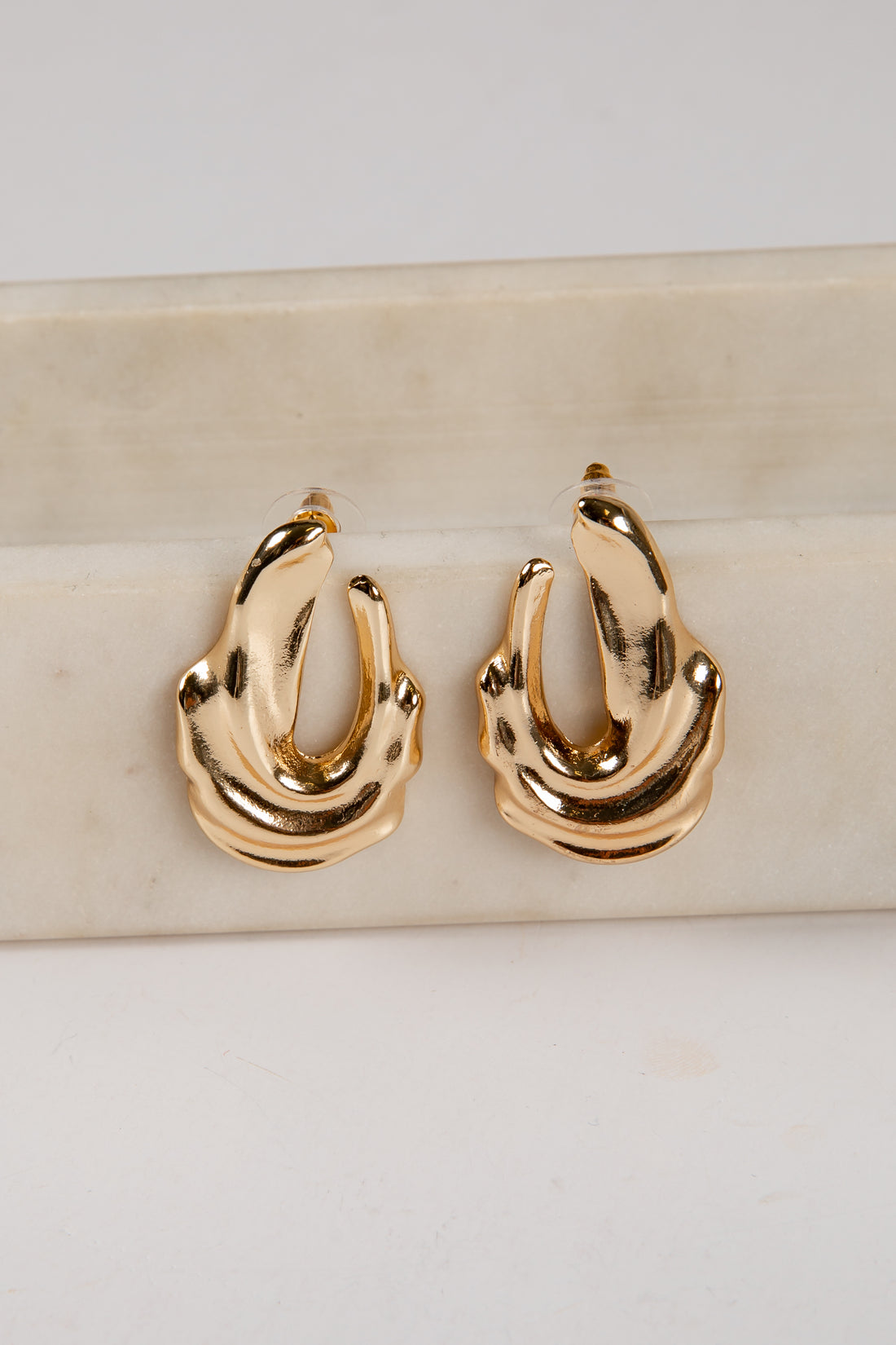 Gold hoop earrings on a marble surface