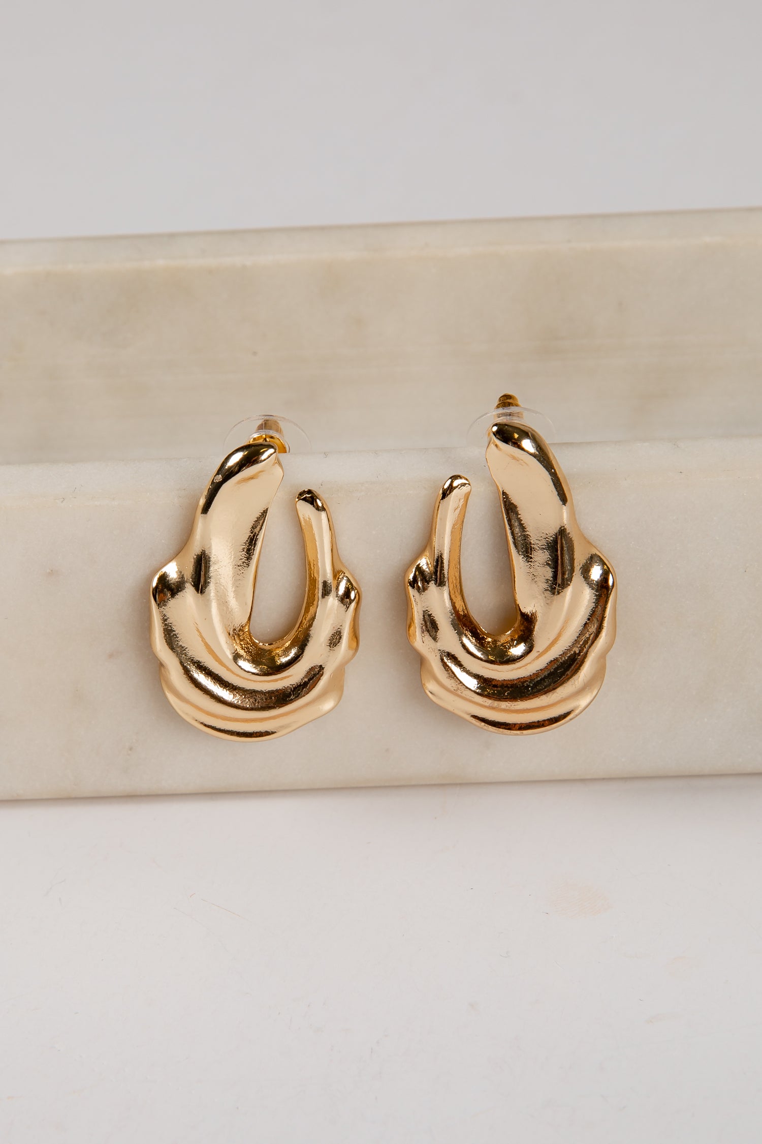 Gold hoop earrings on a marble surface