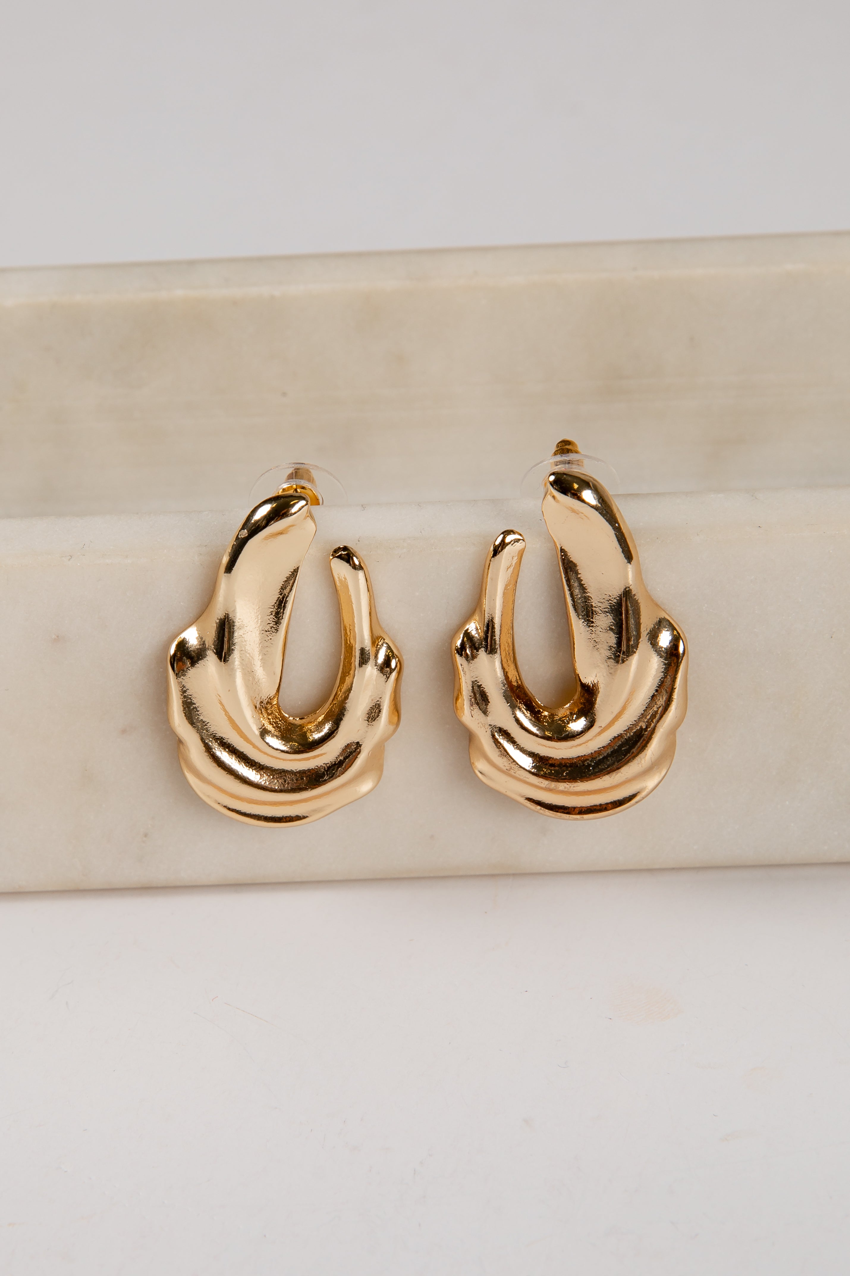 Gold hoop earrings on a marble surface