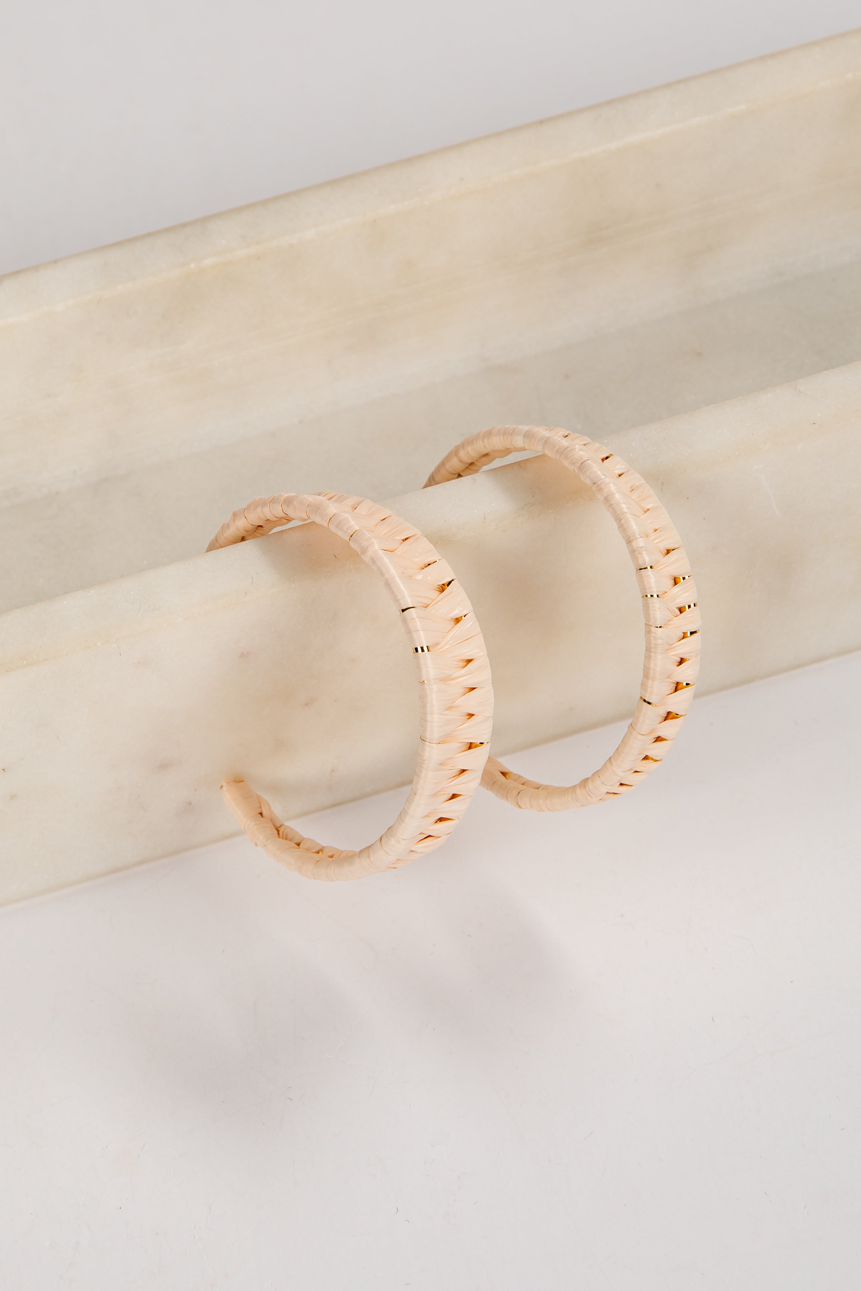 Pair of gold hoop earrings on a light wooden surface