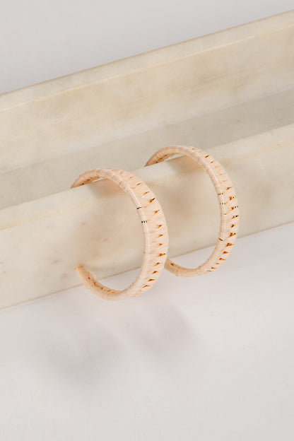 Pair of gold hoop earrings on a light wooden surface