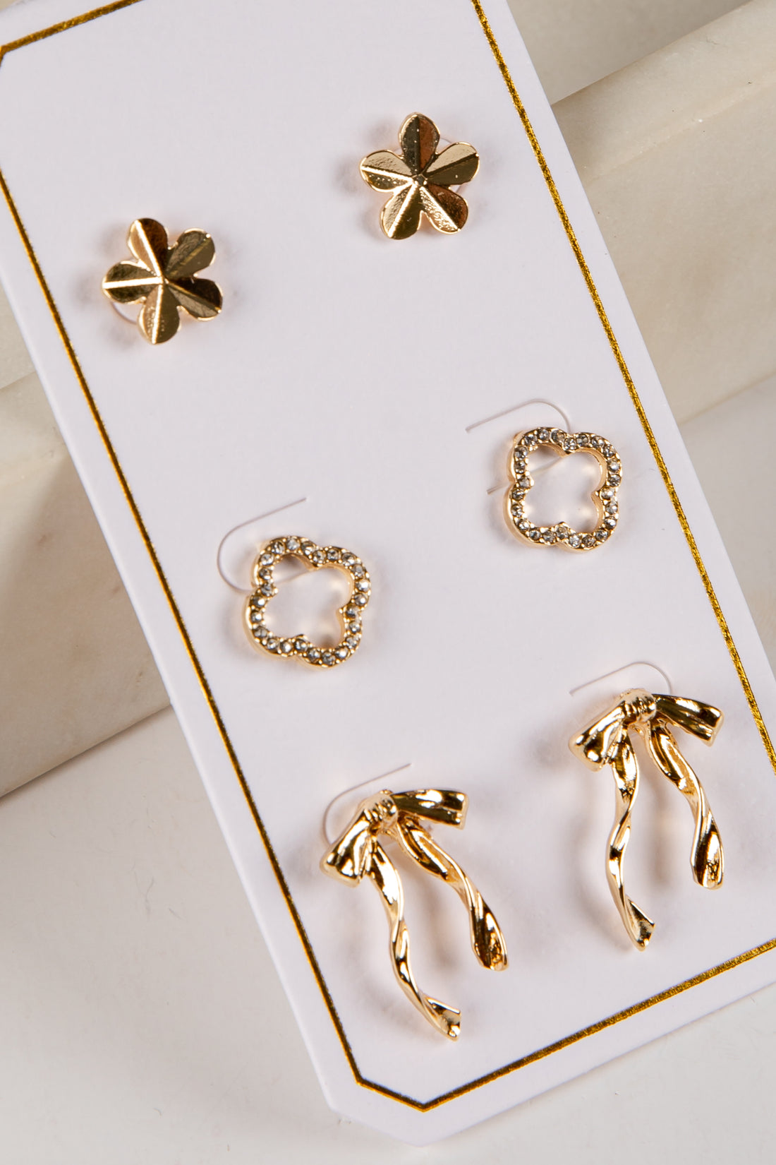 Set of gold earrings on a white card with gold trim