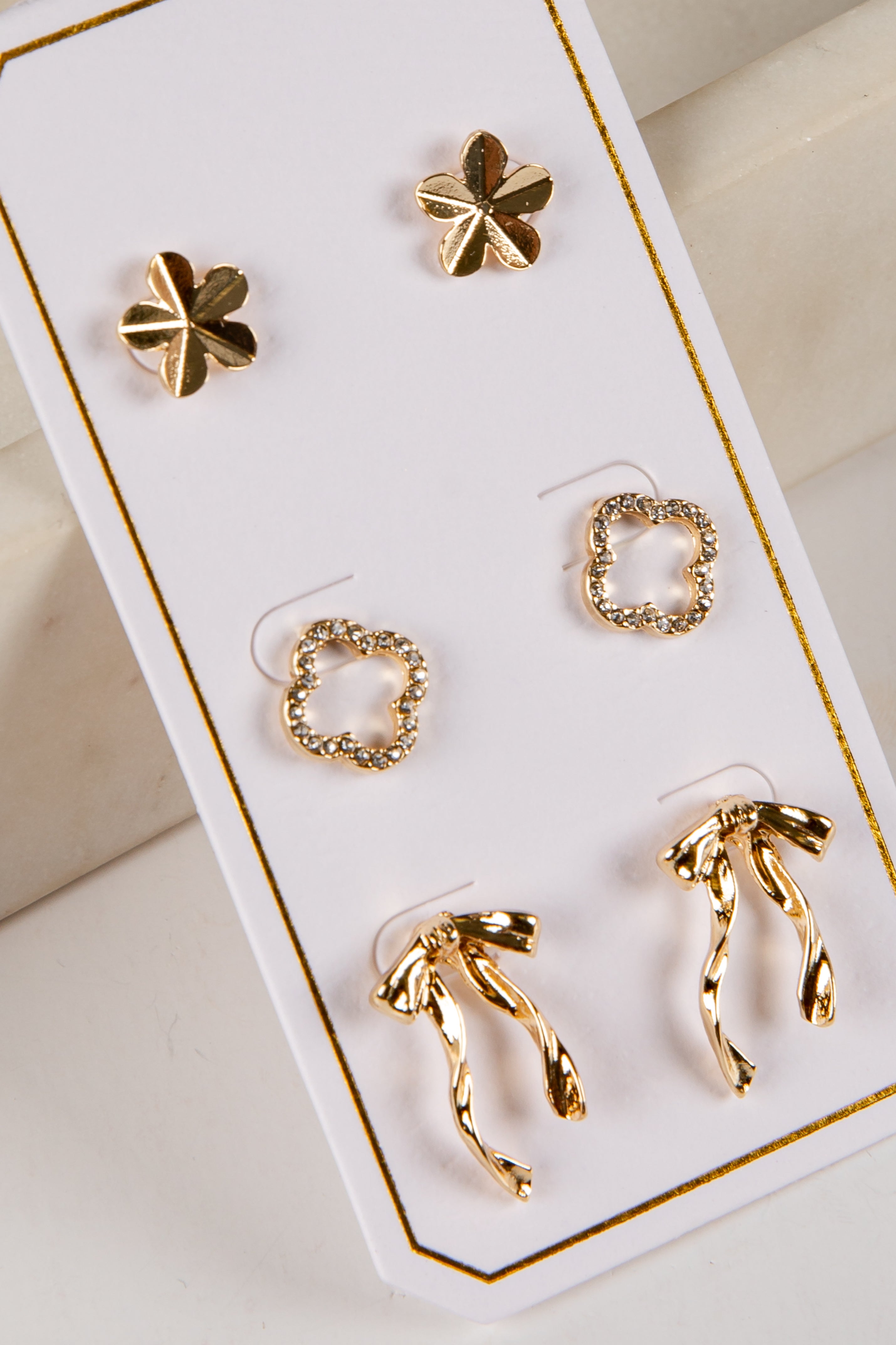 Set of gold earrings on a white card with gold trim
