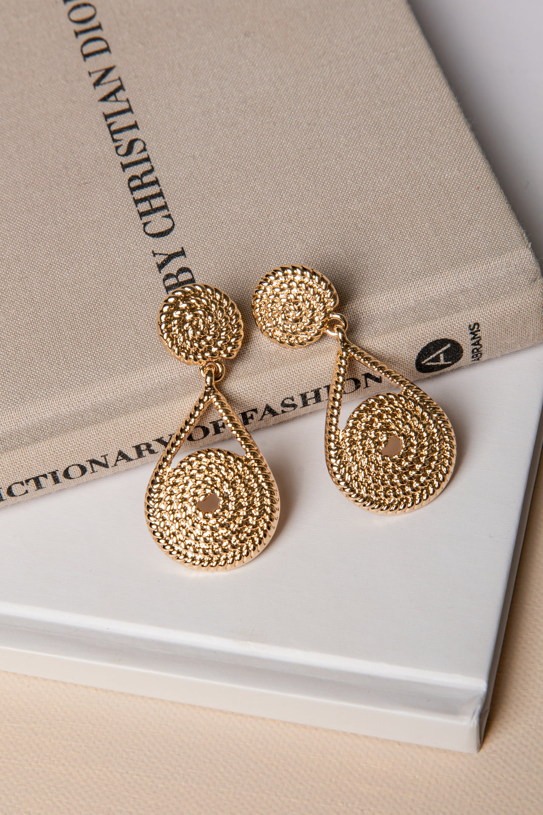 Gold earrings on a book with &