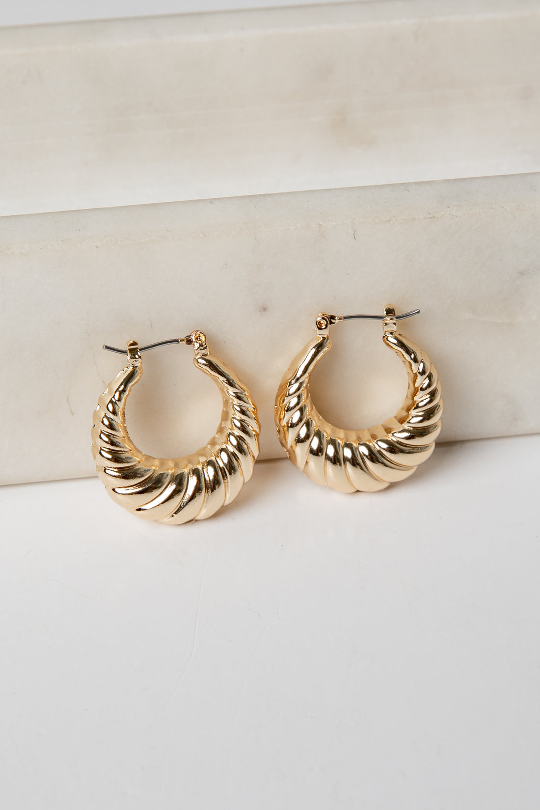 Gold hoop earrings on a light background