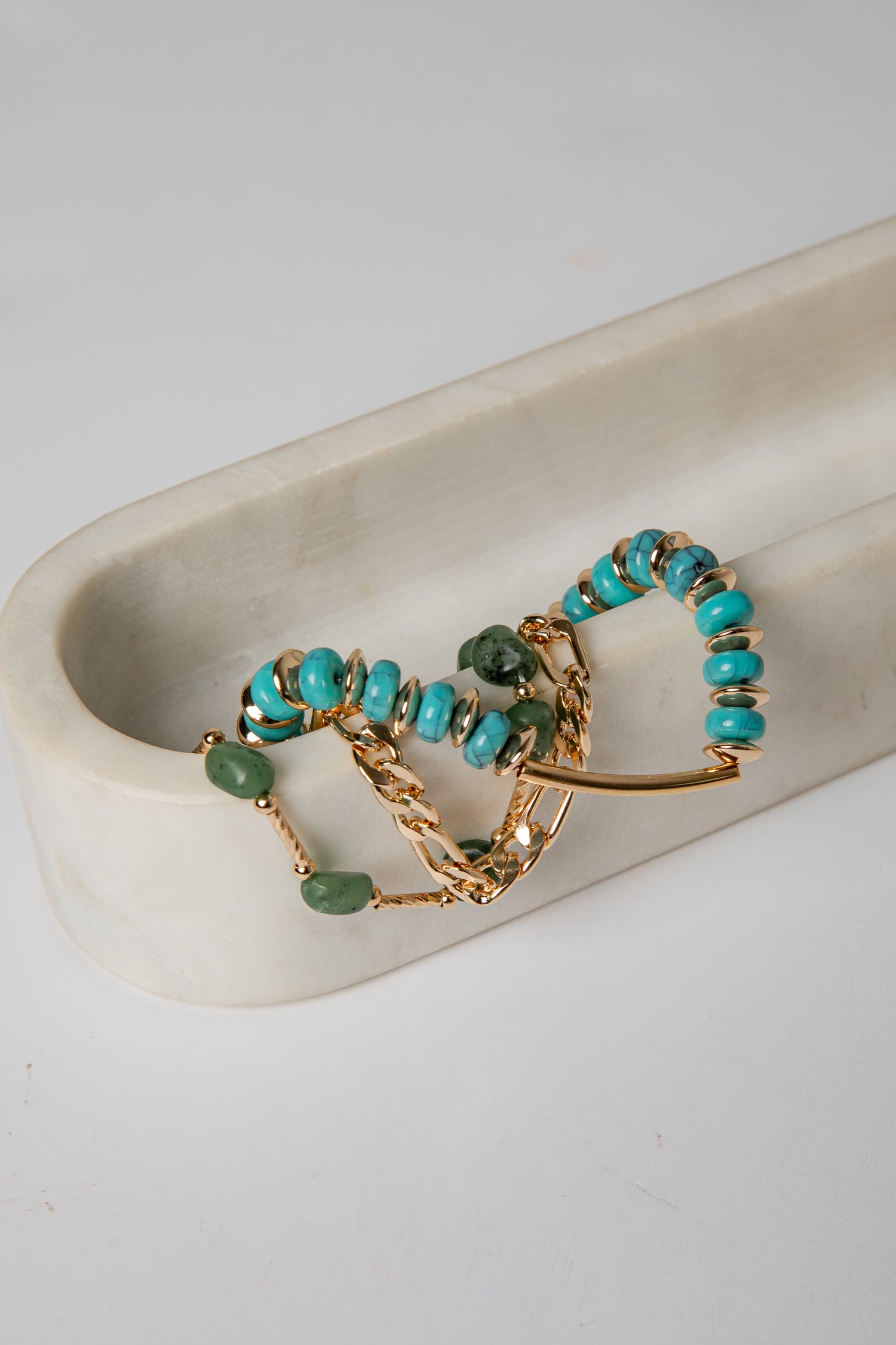 Gold and turquoise beaded jewelry on a white dish