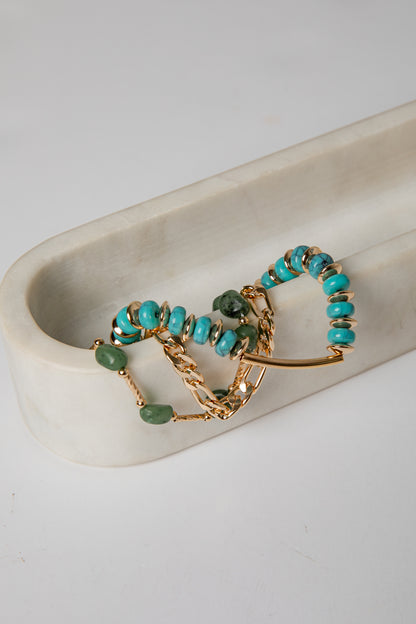 Gold and turquoise beaded jewelry on a white dish