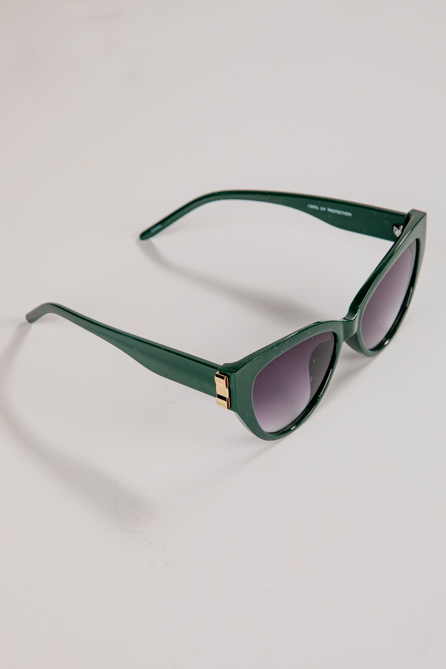 Green sunglasses with dark lenses on a light gray background