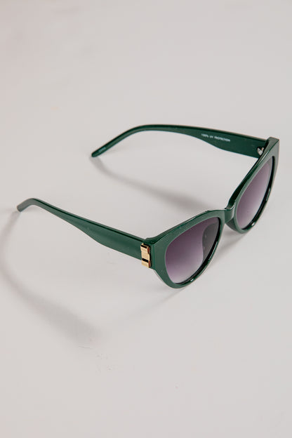 Green sunglasses with dark lenses on a light gray background