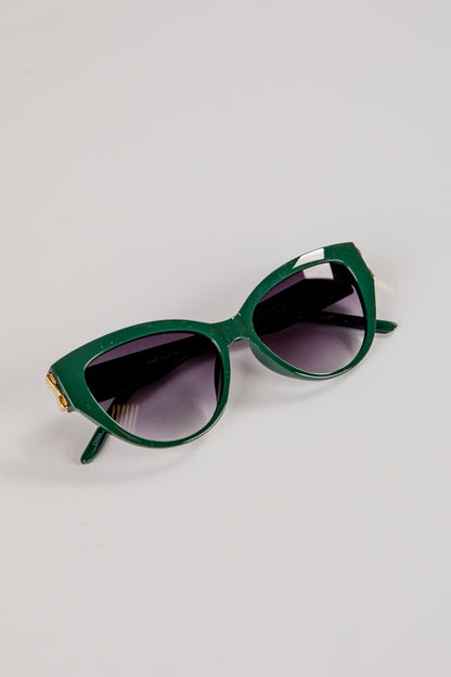 Green sunglasses with dark lenses on a light gray background
