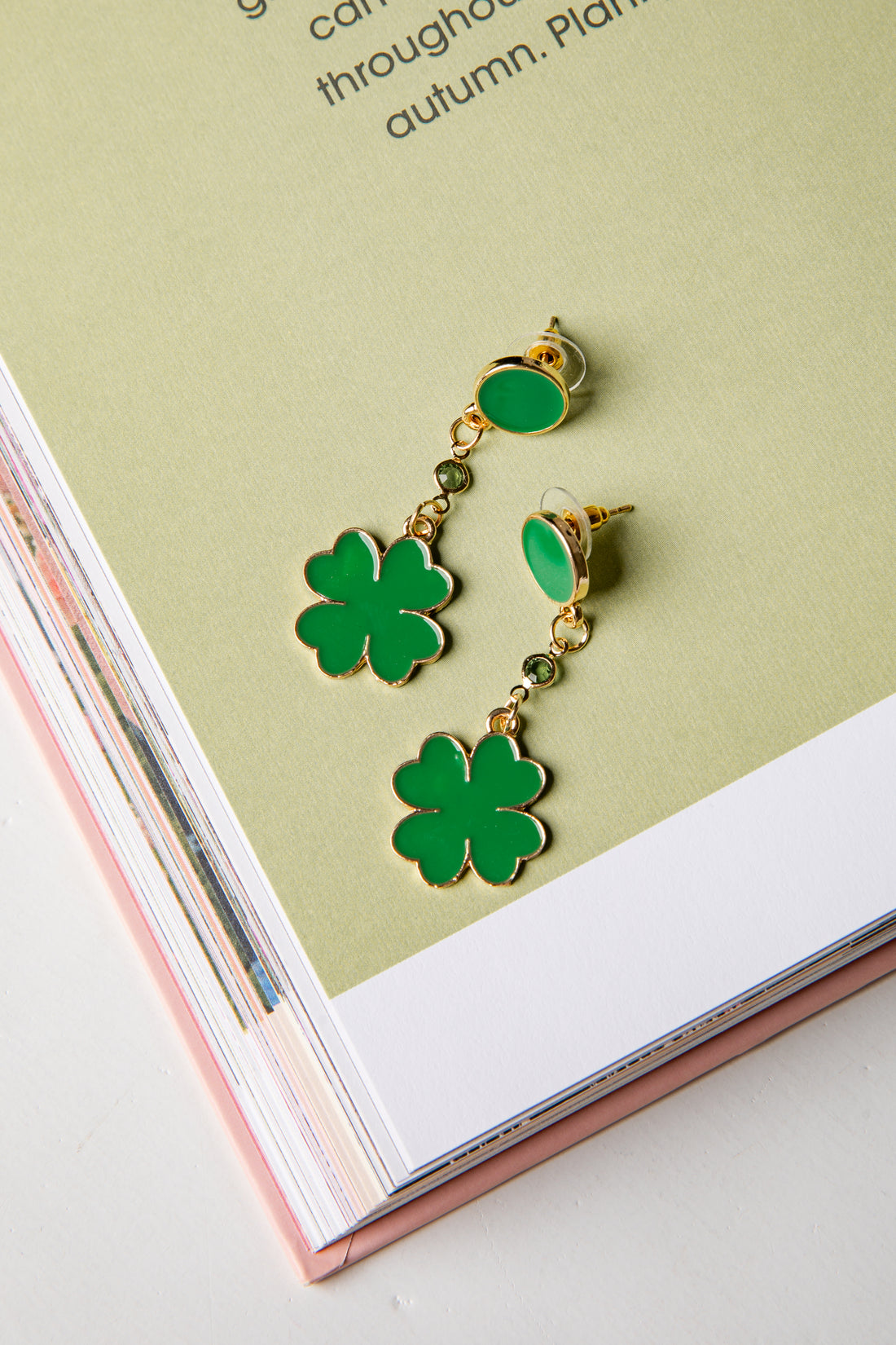 Green four-leaf clover earrings on a magazine page