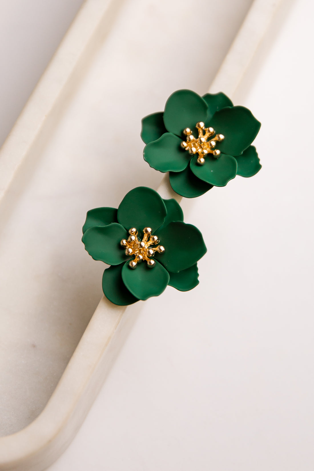 Green floral earrings with gold centers on a white background