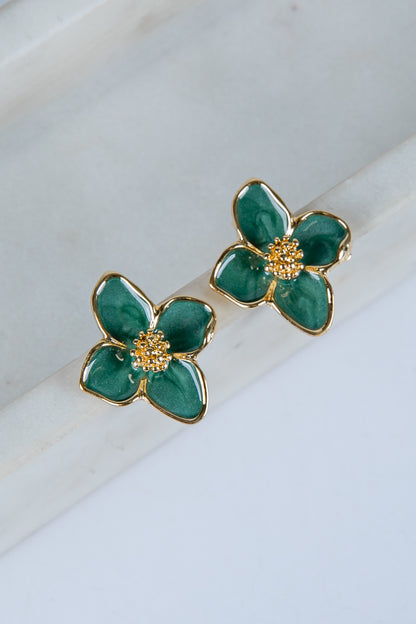 Green flower-shaped earrings with gold accents on a marble surface