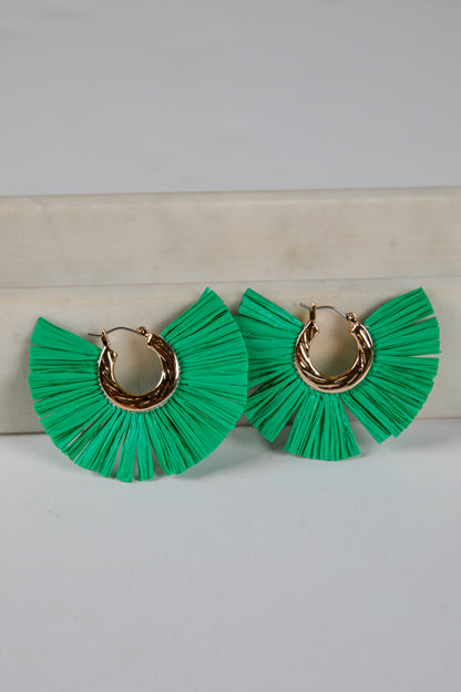 Green ruffled earrings with gold hoop centers on a light gray background
