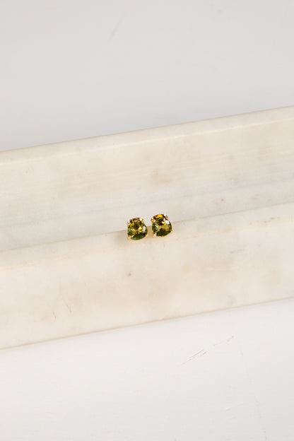 Pair of green gemstone stud earrings on a white marble surface