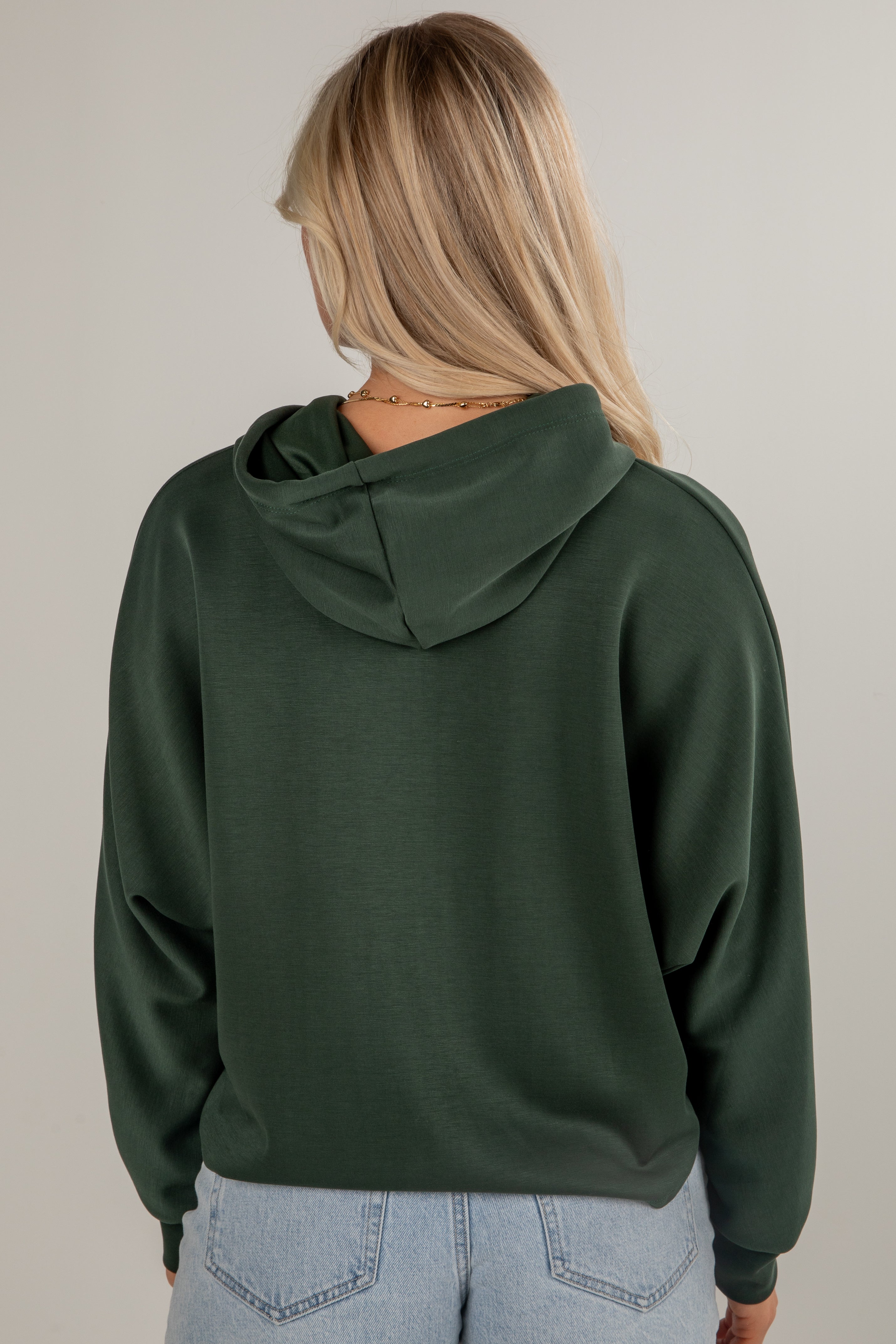 Person wearing a green hoodie from behind on a plain background