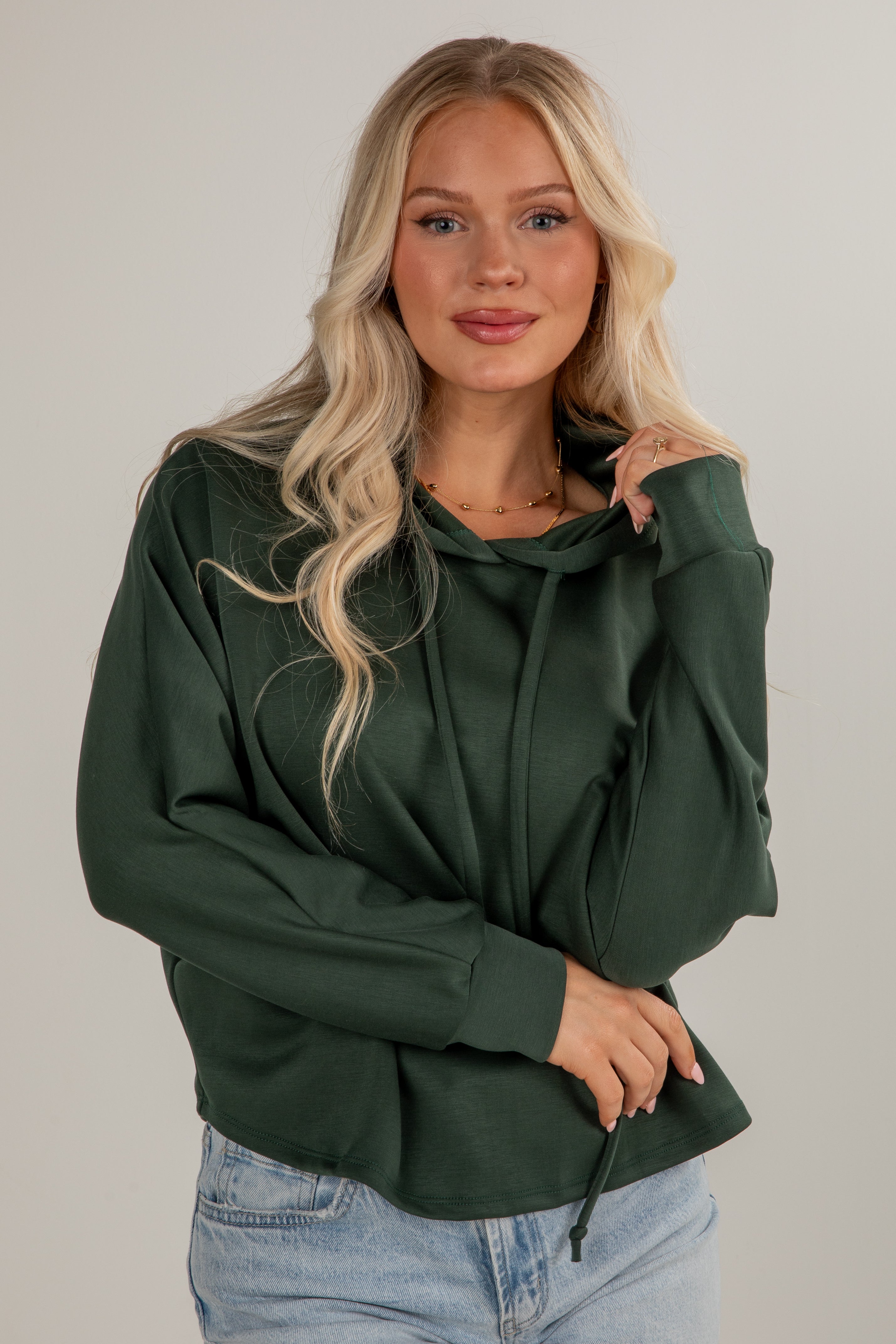 Woman wearing a green hoodie against a plain background