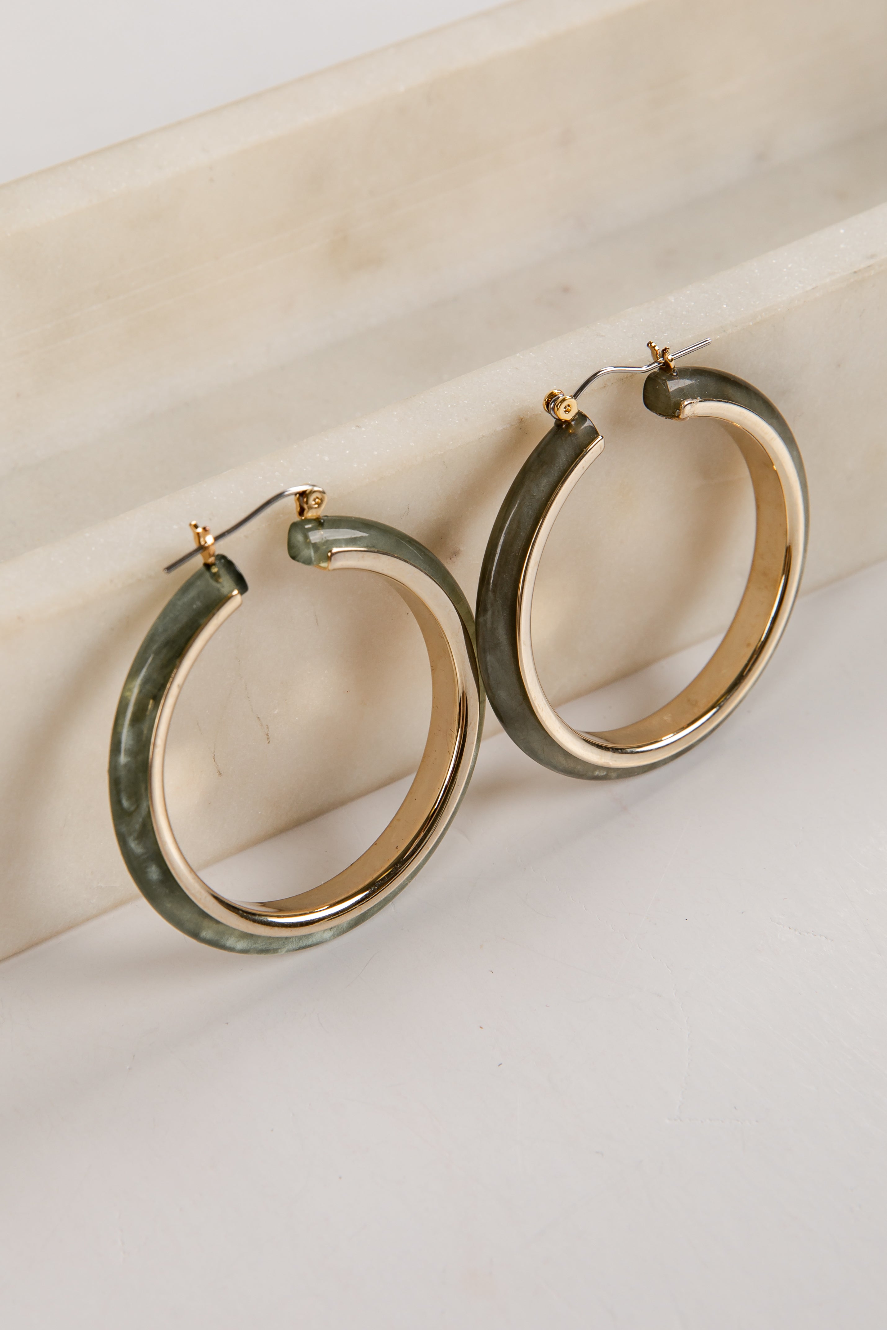 Hoop earrings with green and gold finish on a light background