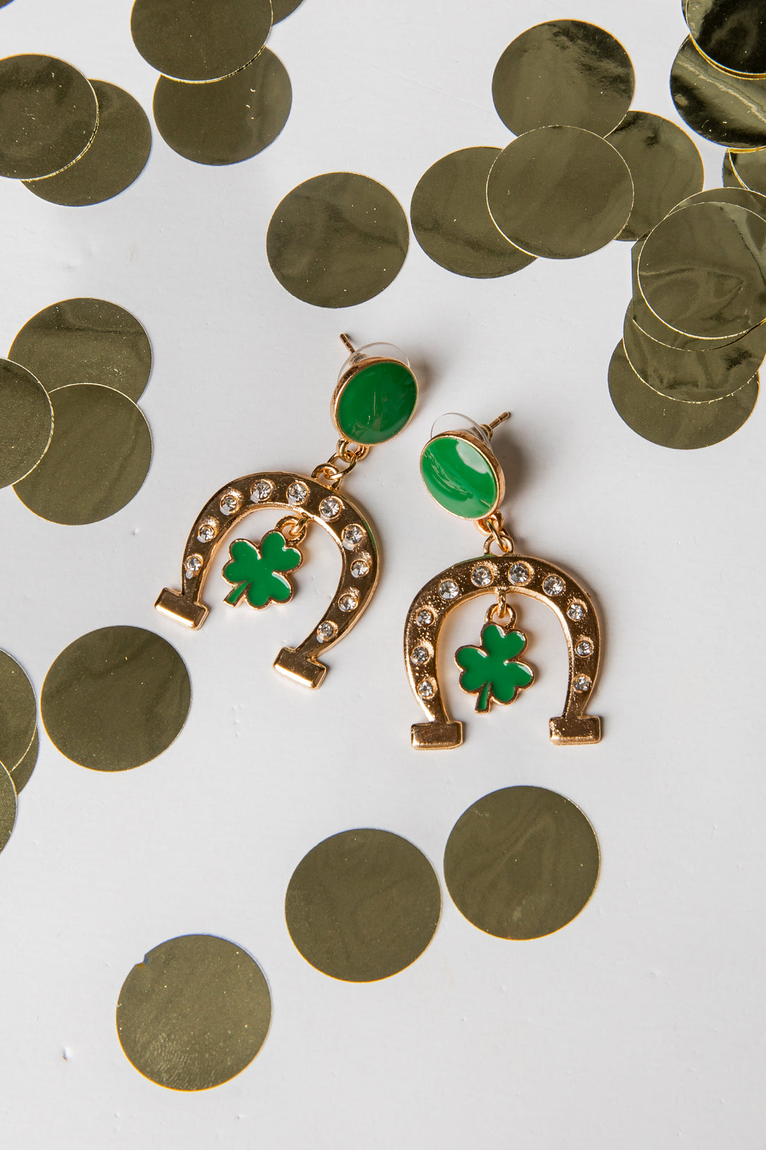 Gold earrings with green clover leaves on a white background with gold coins.