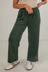 Person wearing green wide-leg pants with a plain background