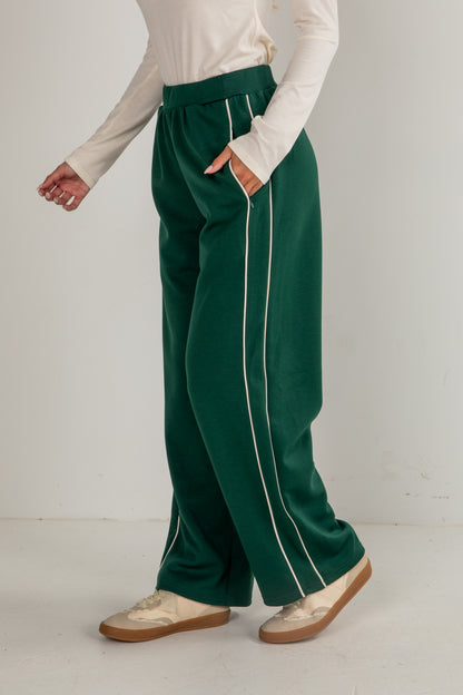 Person wearing green pants with white stripes on a plain background