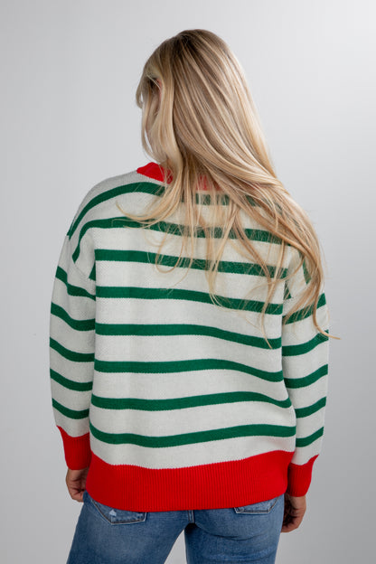 Person wearing a green and red striped sweater on a plain background