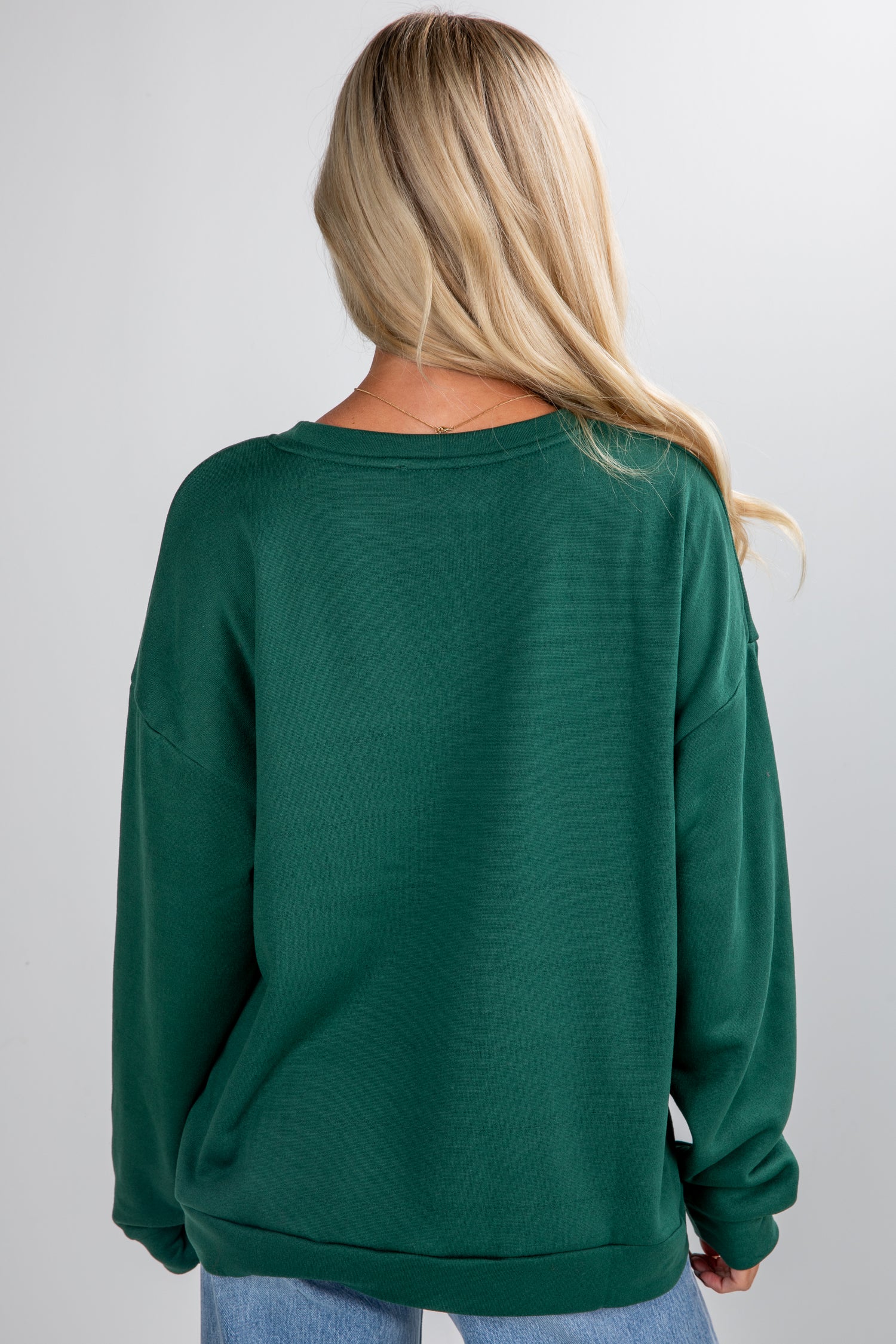 Person wearing a green sweatshirt on a plain background