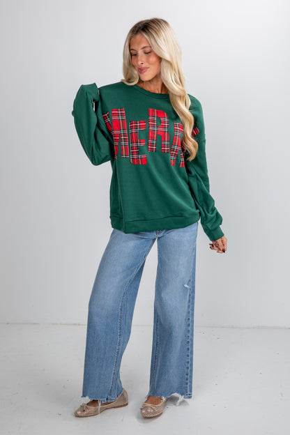 Woman wearing a green sweatshirt with plaid lettering and blue jeans on a white background