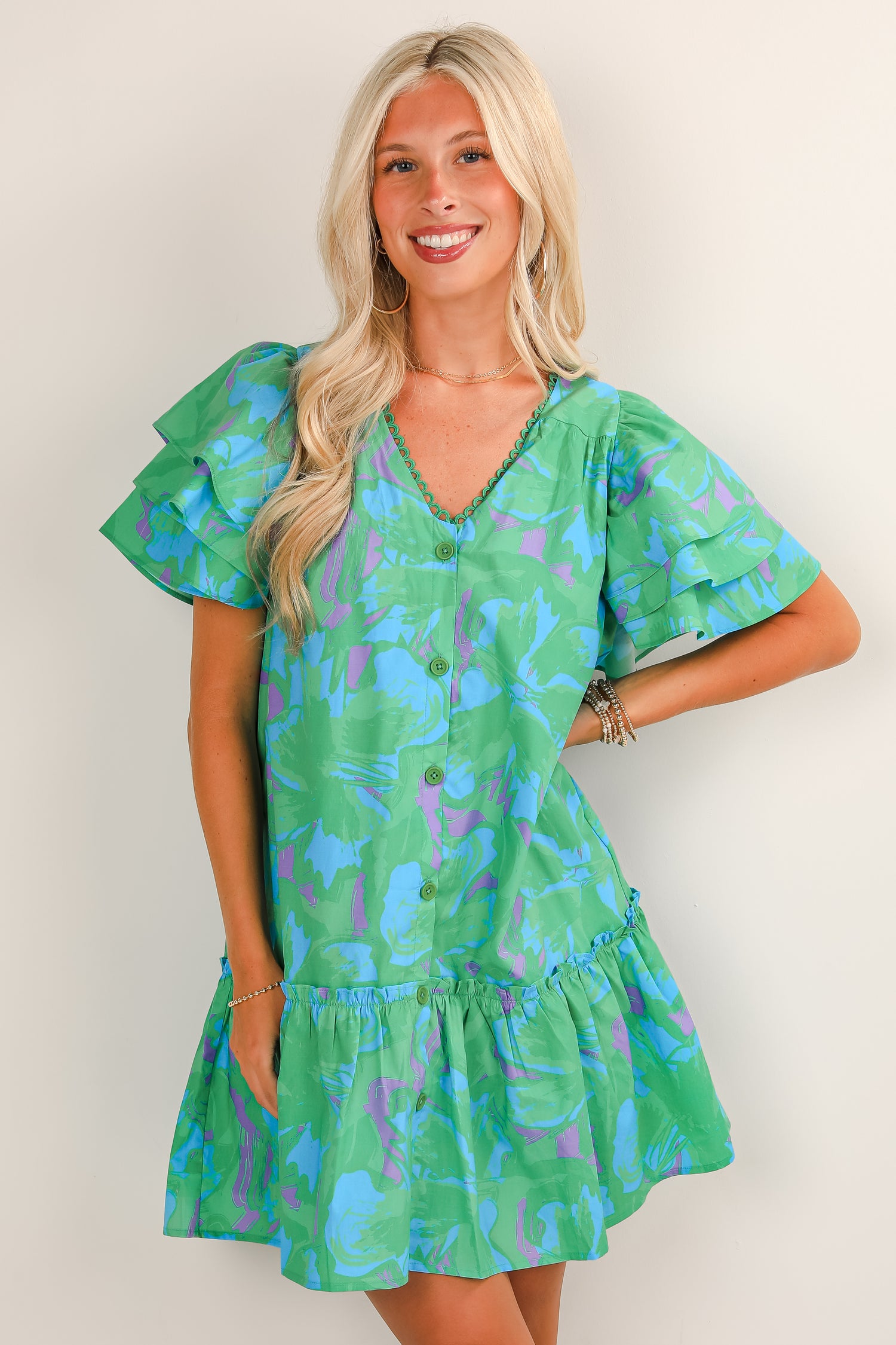 Woman wearing a green floral dress against a plain background