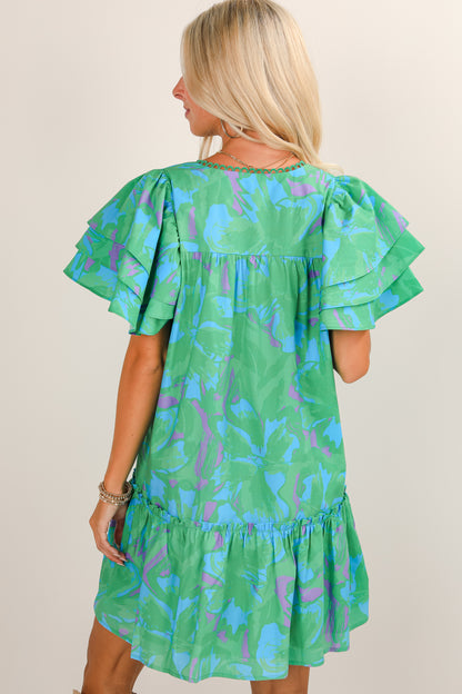 Woman wearing a green dress with blue and purple abstract pattern on a beige background