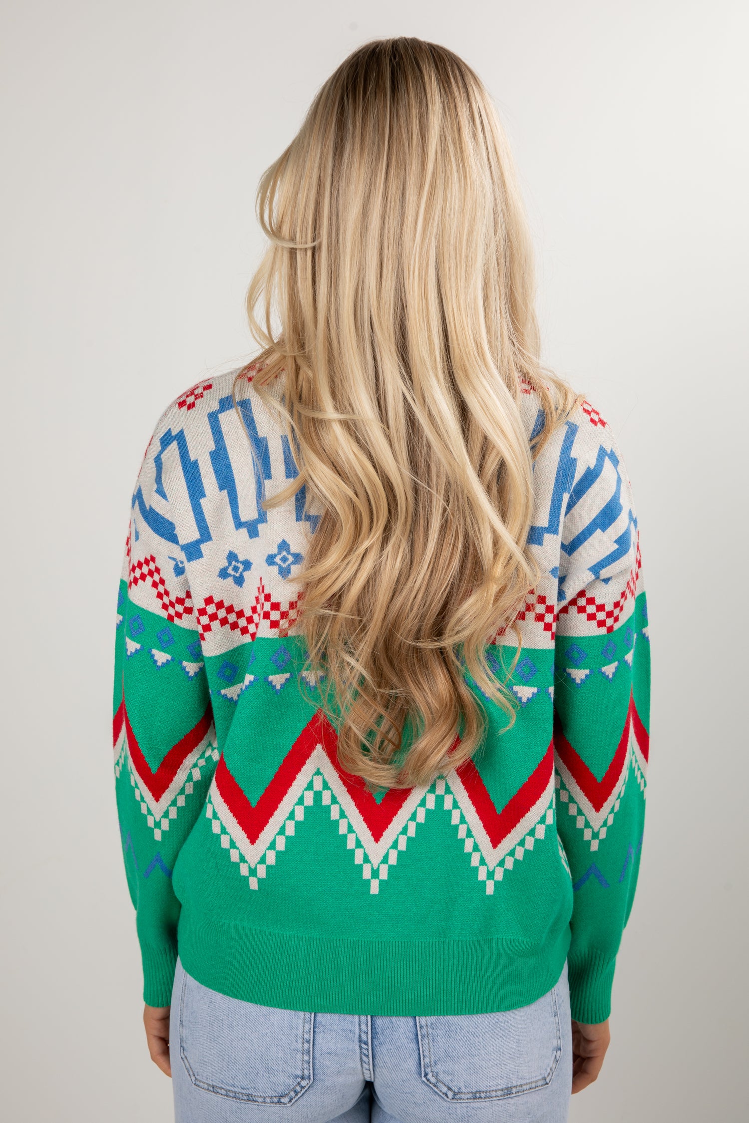 Person wearing a colorful patterned sweater with a plain background