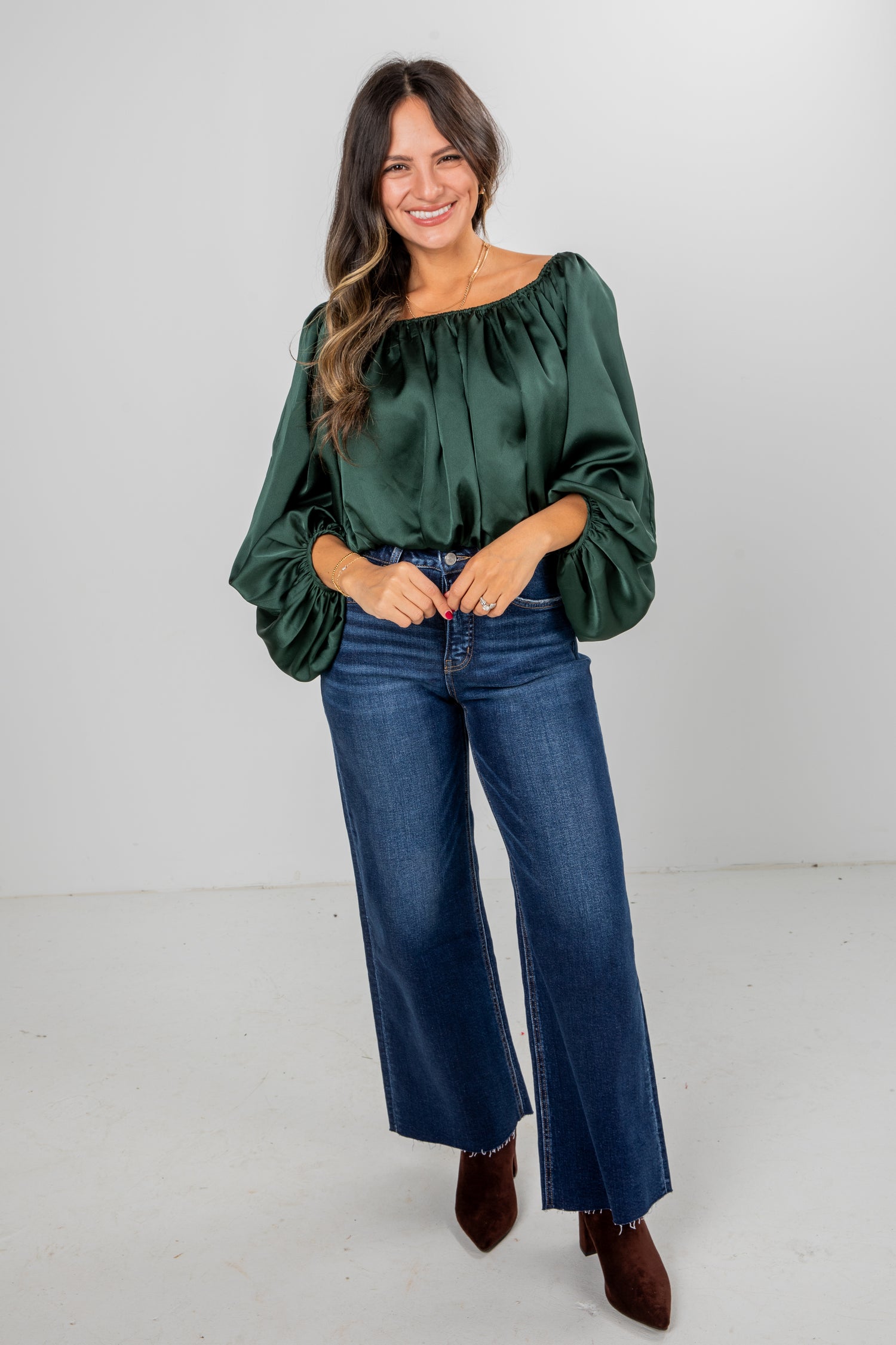 Woman wearing a green blouse and blue jeans on a white background