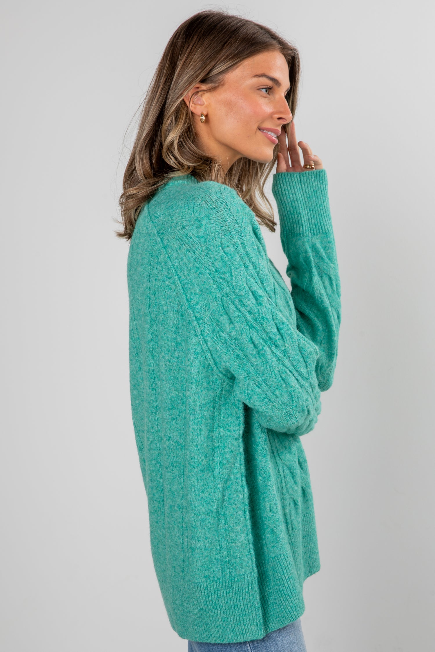 Woman wearing a teal cardigan on a plain background