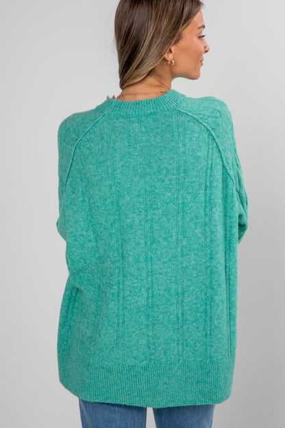 Person wearing a teal sweater on a plain background