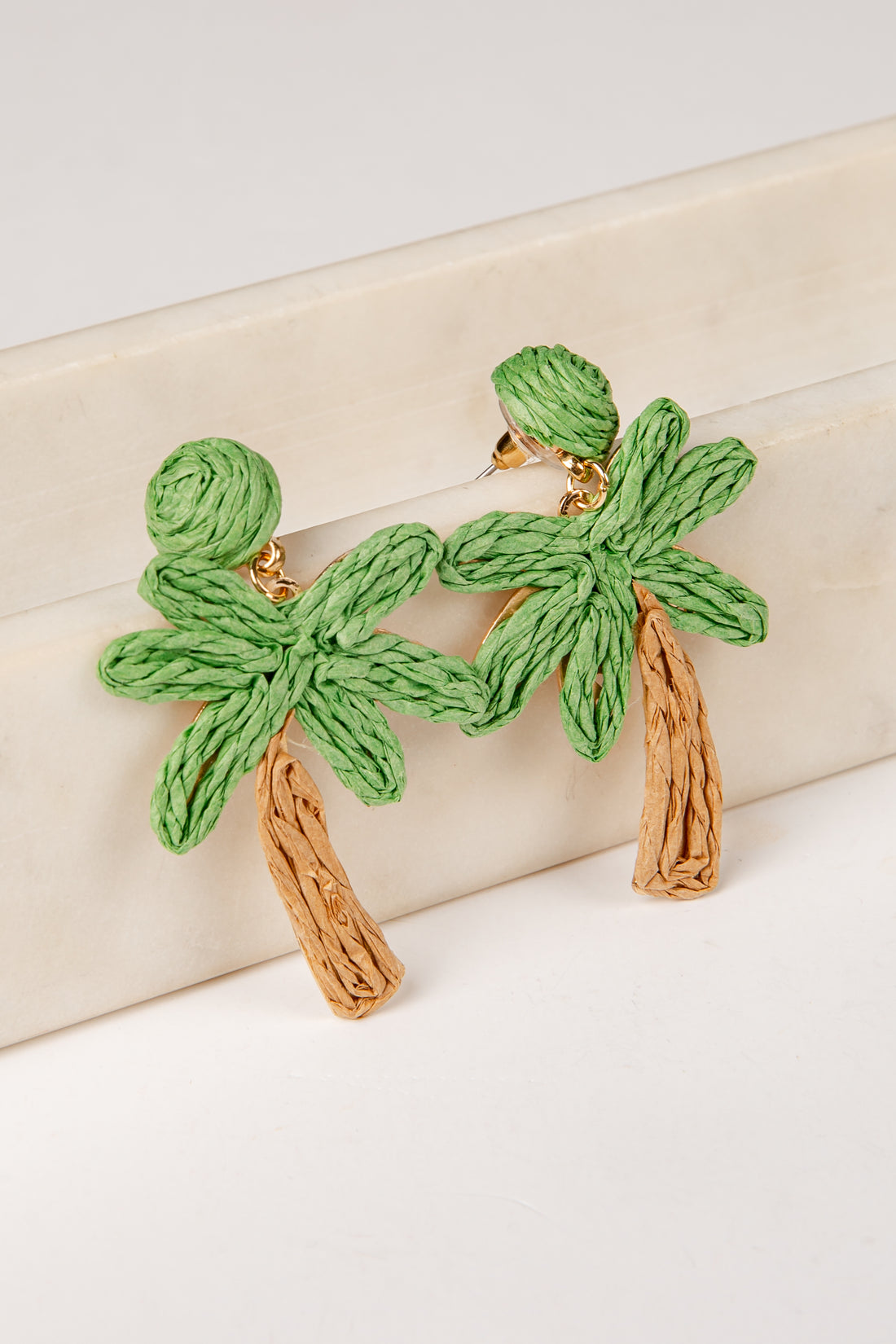 Green palm tree earrings on a beige background