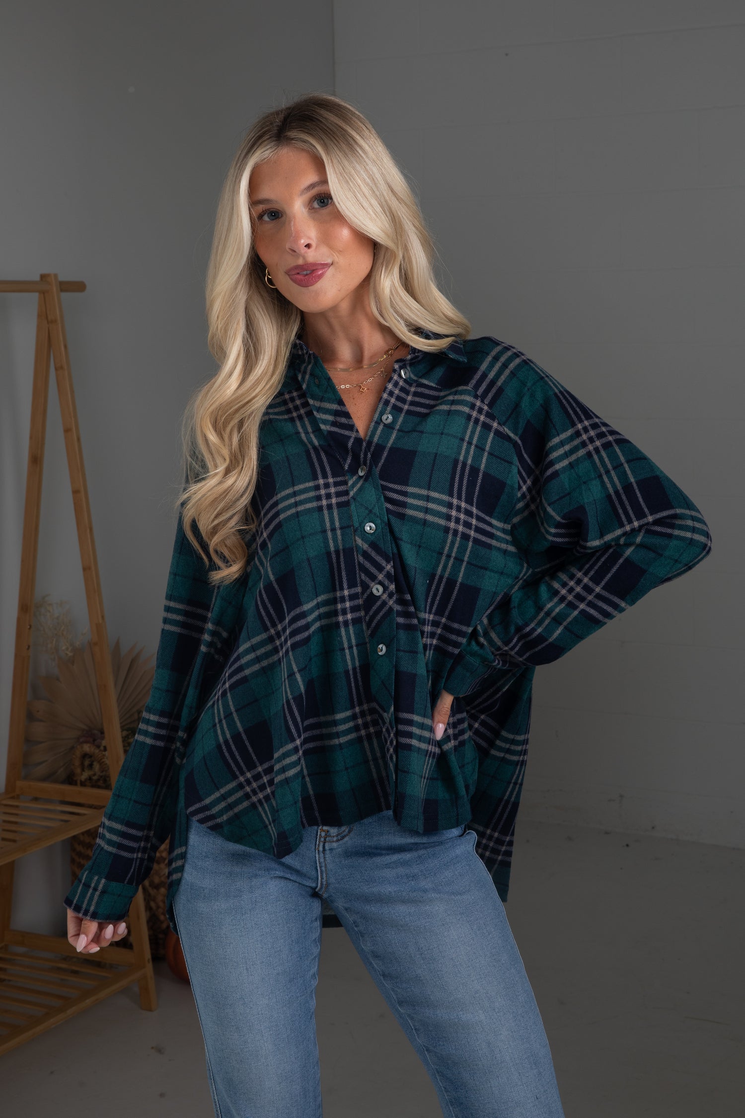 Woman wearing a green plaid shirt and blue jeans against a gray background