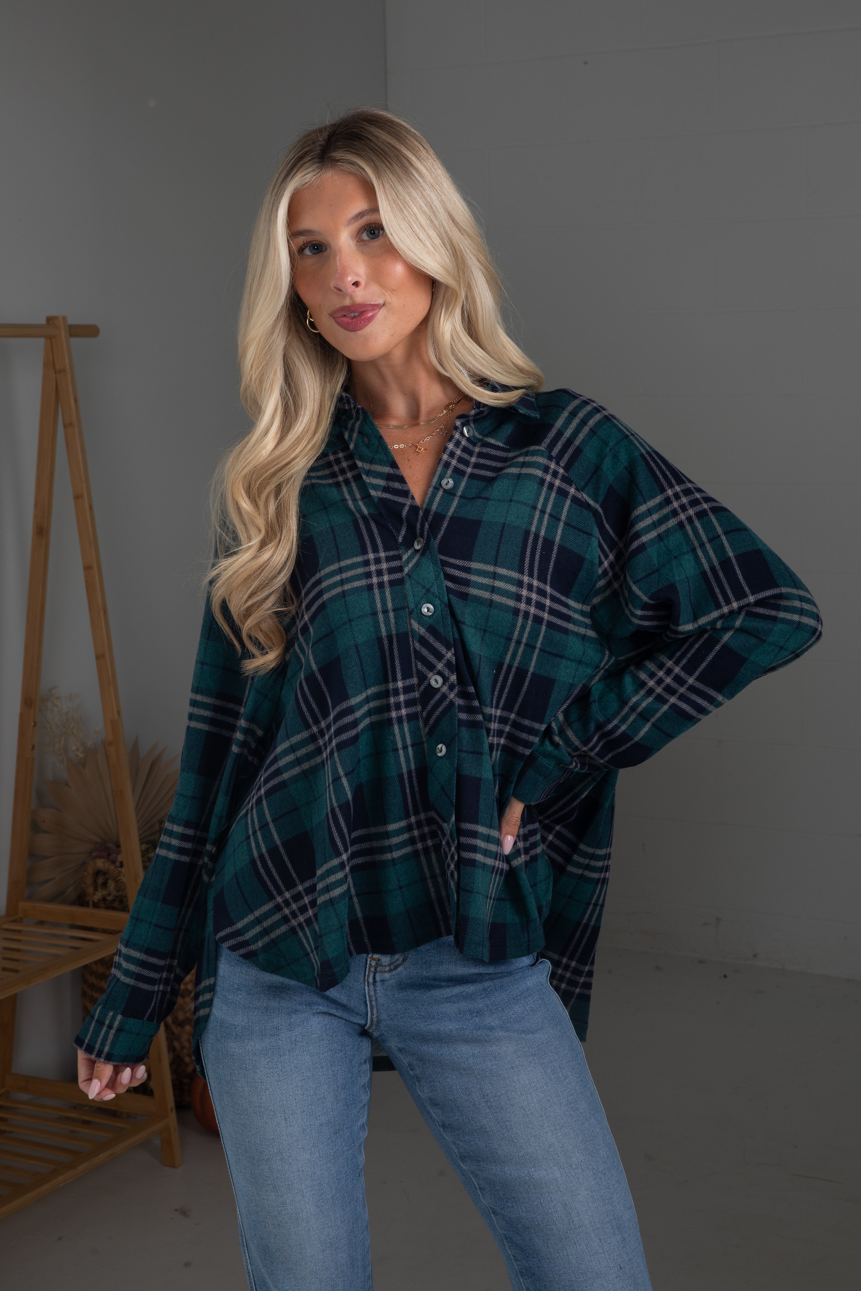 Woman wearing a green plaid shirt and blue jeans against a gray background