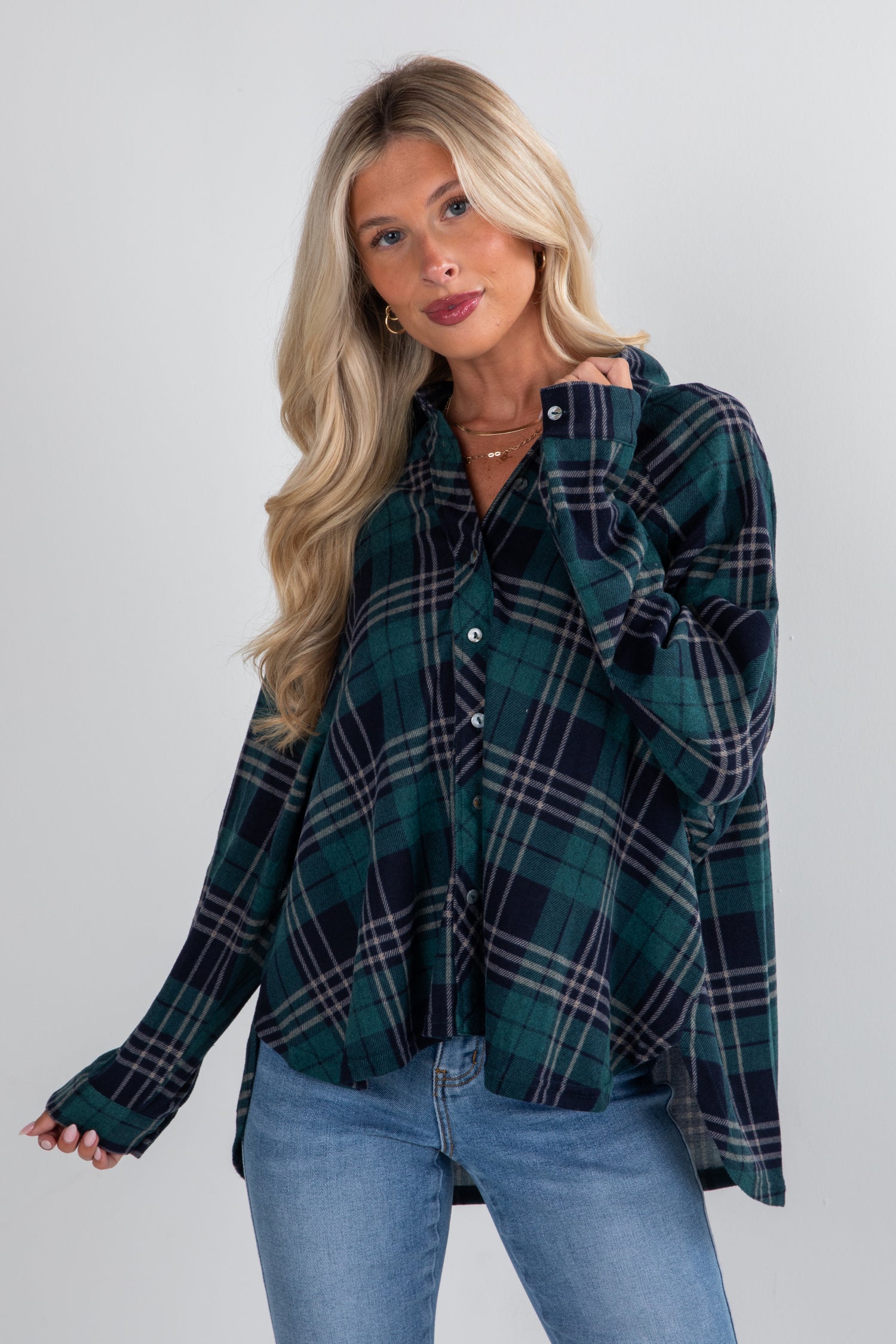 Woman wearing a green plaid shirt and blue jeans against a white background