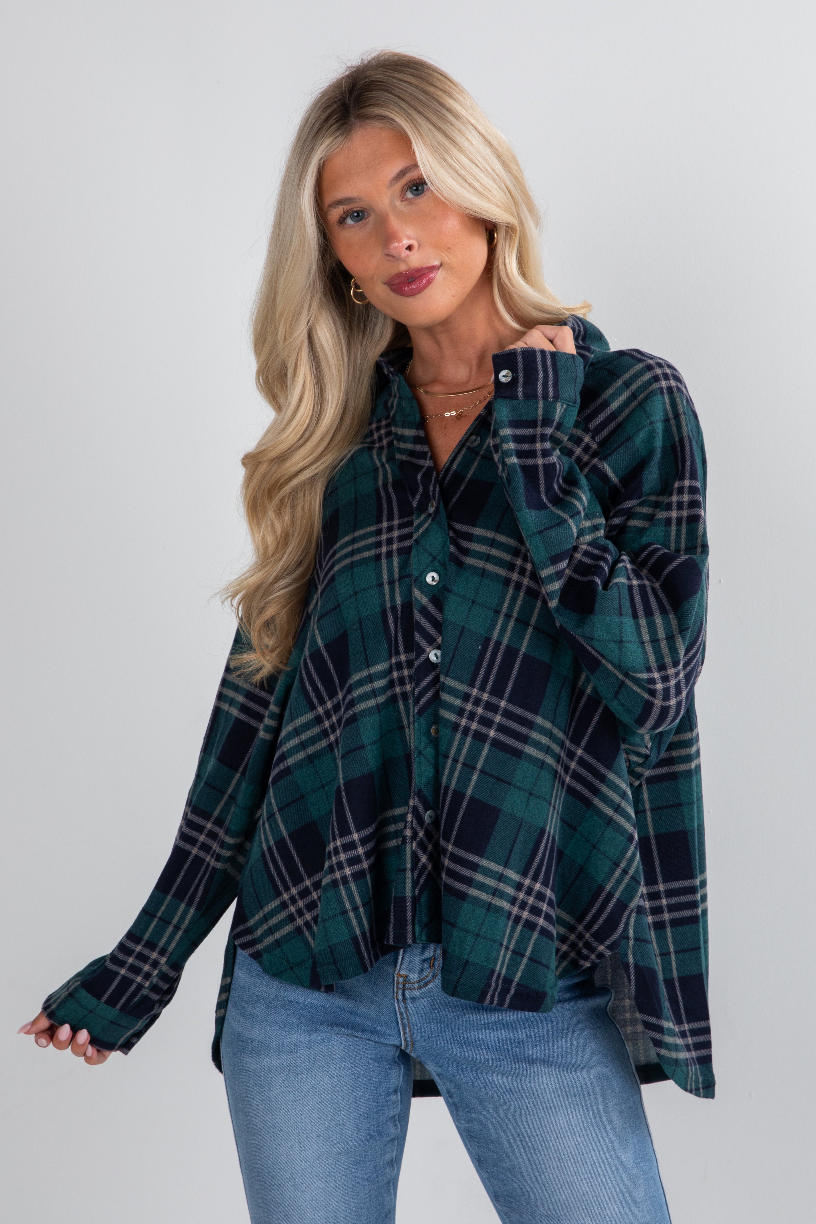 Woman wearing a green plaid shirt and blue jeans against a white background