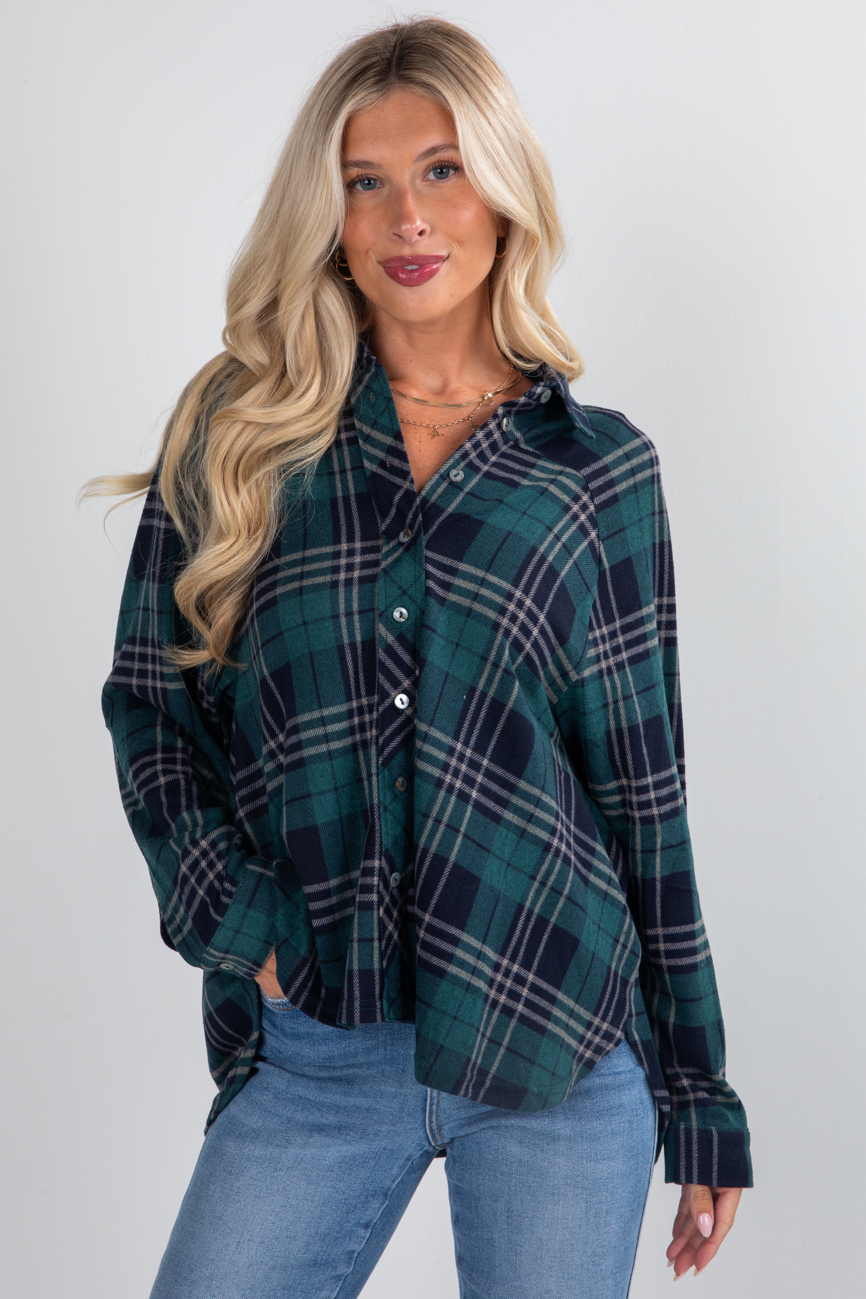 Woman wearing a green plaid shirt and blue jeans on a white background